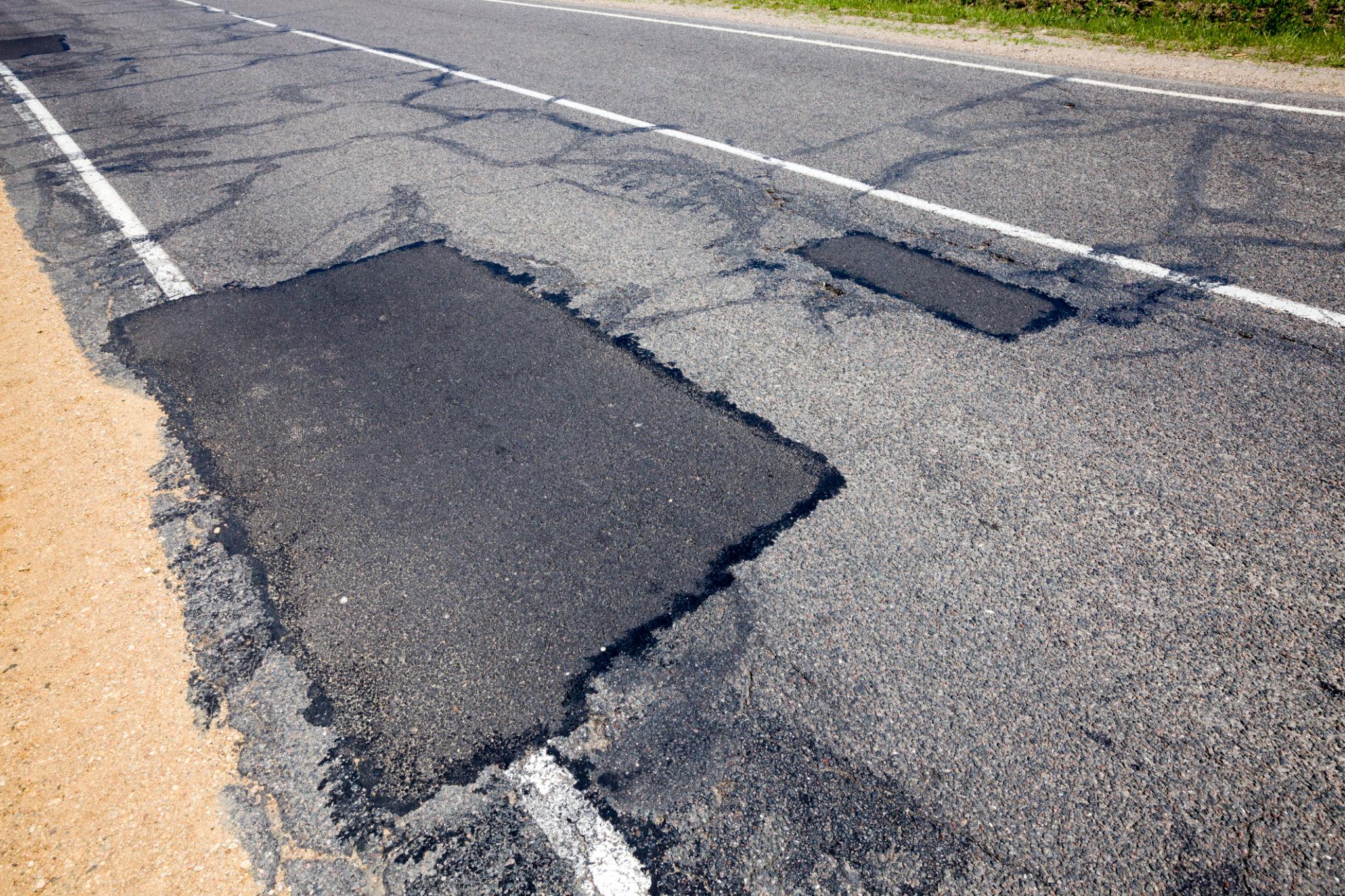 Route dégradée peu après des travaux de réfection, illustrant les conséquences d'une mauvaise gestion des fonds publics et d'infrastructures de faible qualité.