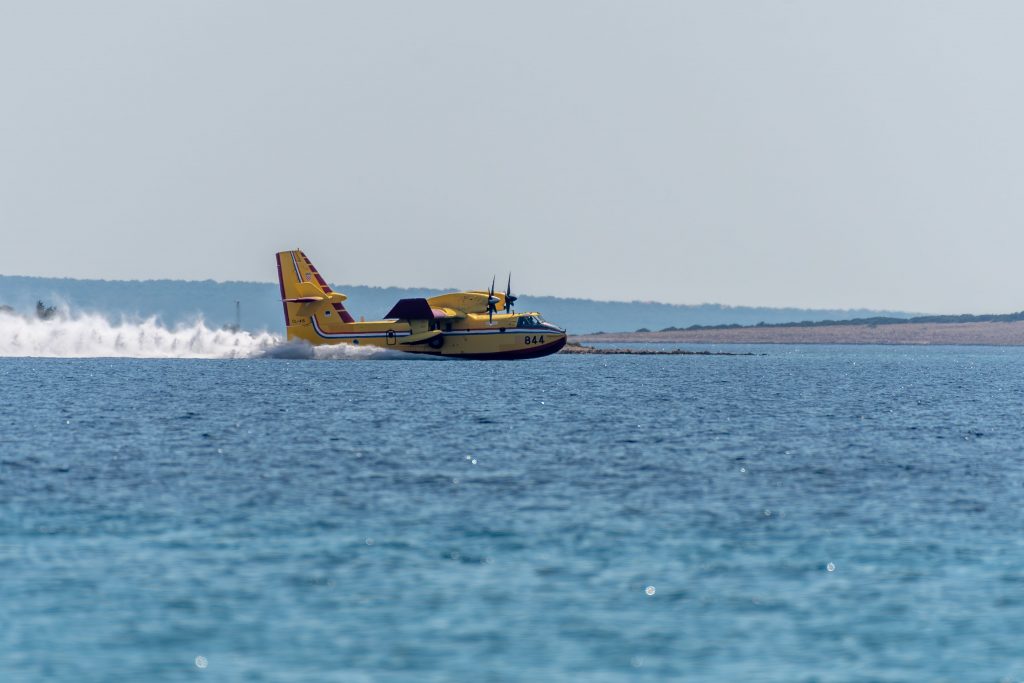 Avion bombardier d’eau jaune rechargeant ses réservoirs à la surface de la mer